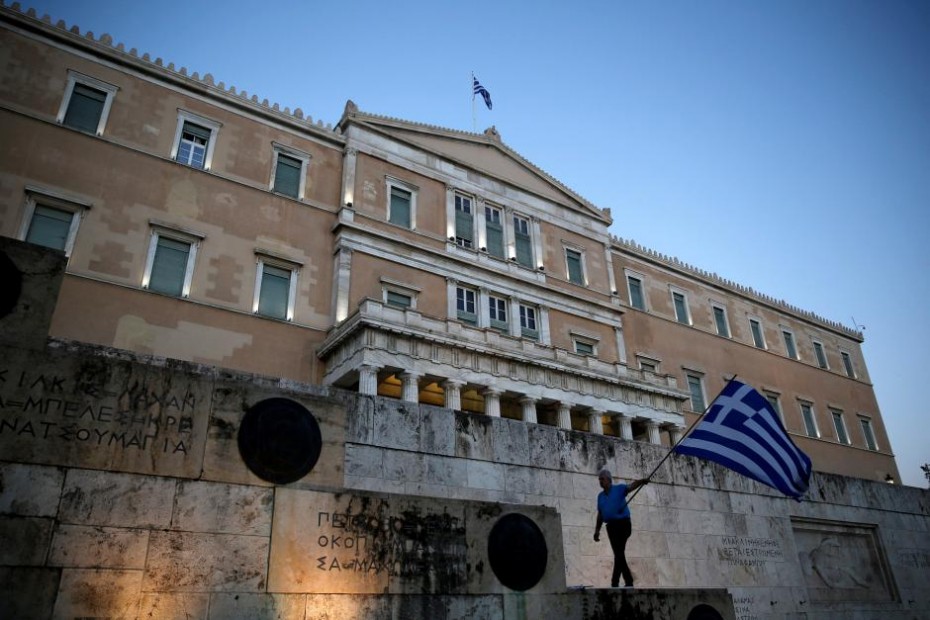 FILE PHOTO: A man waves a Greek flag during an anti-goverment rally outside the Greek parliament building in Athens