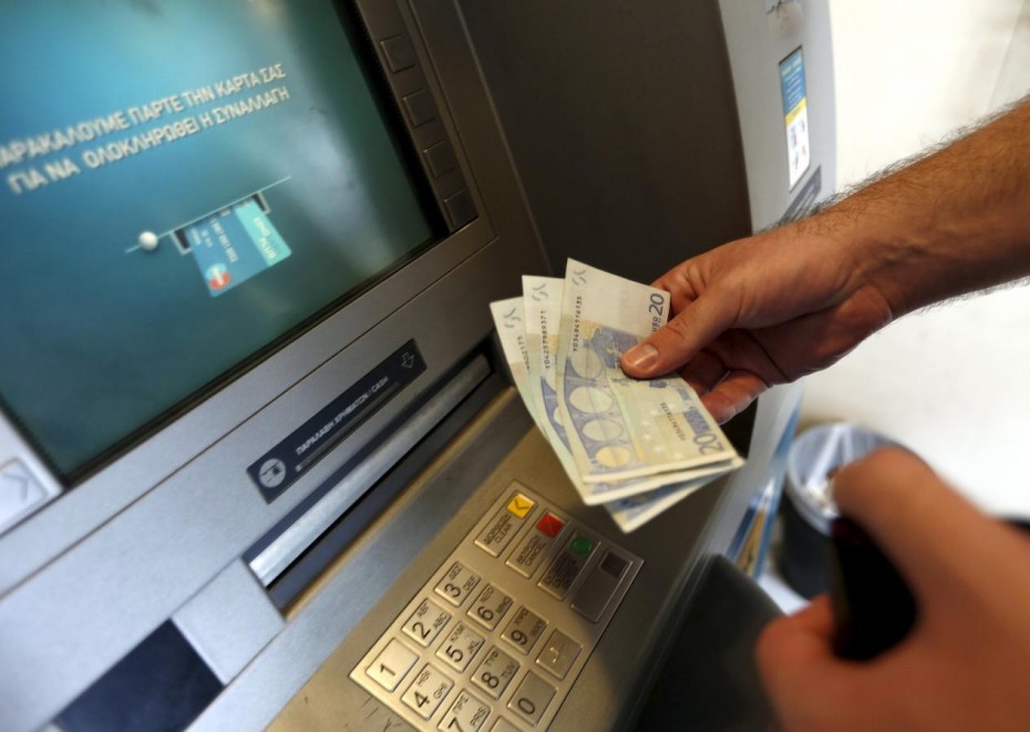 A man withdraws sixty Euros, the maximum amount allowed after the imposed capital controls in Greek banks,  at a National Bank of Greece ATM in Piraeus