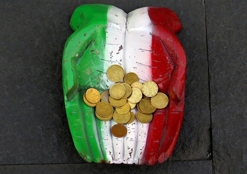 FILE PHOTO: Euro coins are seen on the figure of a pair of hands on the ground in downtown Rome