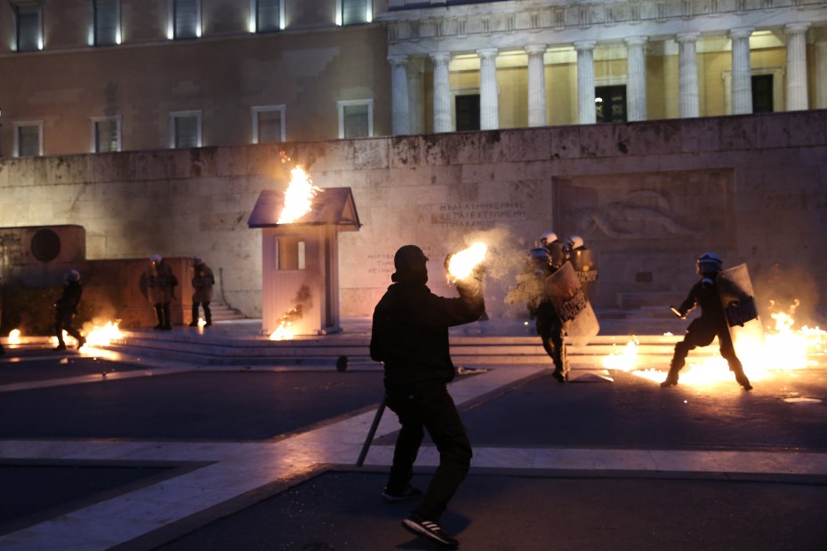 A masked demonstrator throws a petrol bomb to riot police outside the parliament building as Greek lawmakers vote on the latest round of austerity Greece has agreed with its lenders, in Athens