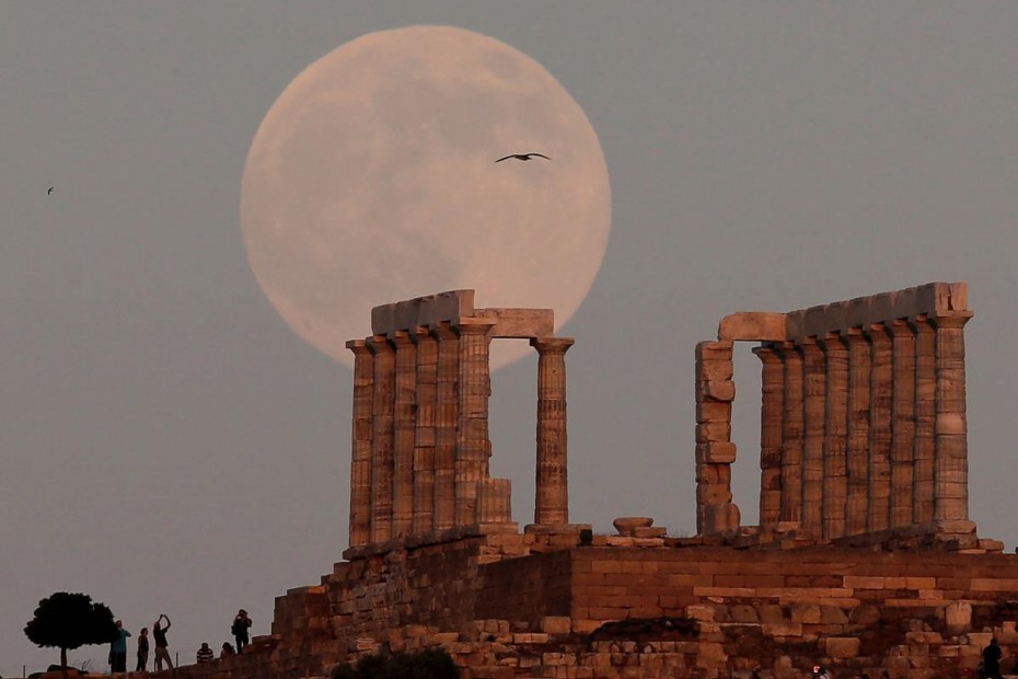 FILE PHOTO: A nearly full moon rises over the Temple of Poseidon, the ancient Greek god of the seas, in Cape Sounion, east of Athens
