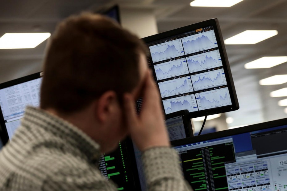 Traders looks at financial information on computer screens on the IG Index the trading floor