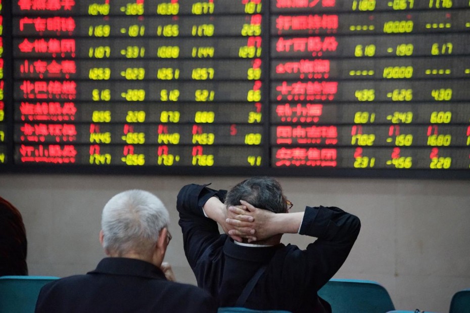 Investors look at an electronic board showing stock information at a brokerage house in Nanjing